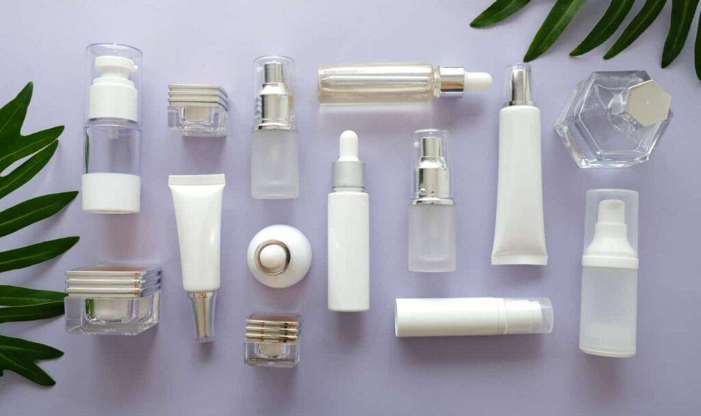 cosmetic packaging set on purple background. group of skincare cream serum oil . facial beauty cosmetic spa product. natural cosmetology concept skin treatment with green leaf and laboratory science glassware.